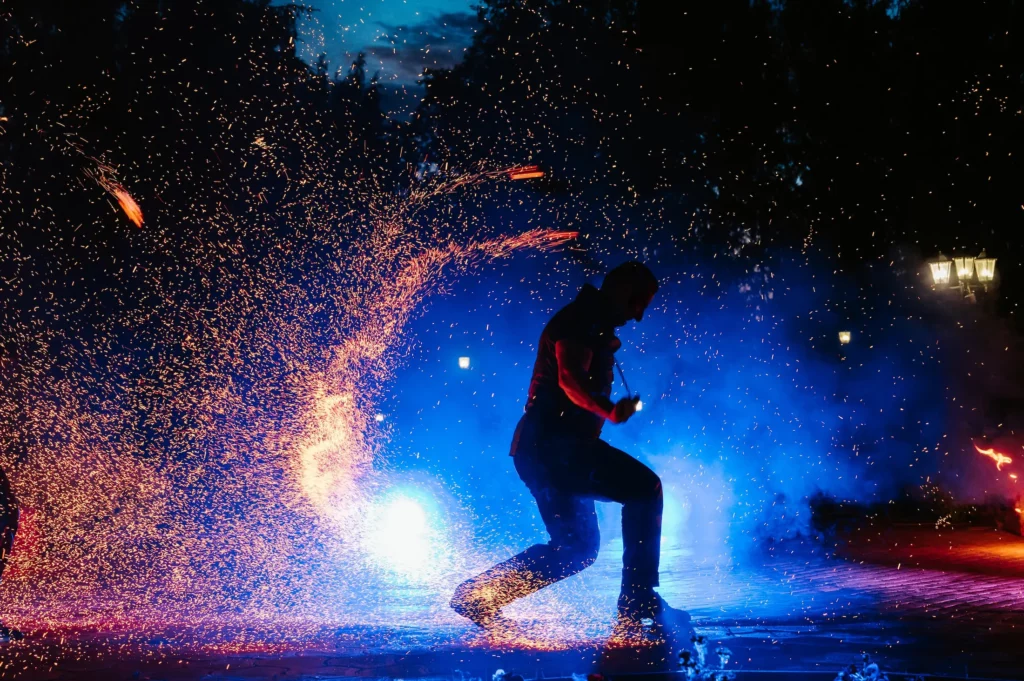 spettacolo con fuoco personalizzato con fuoco e luci elvis fa ruotare delle catene con il fuoco all'estremità illuminando la notte