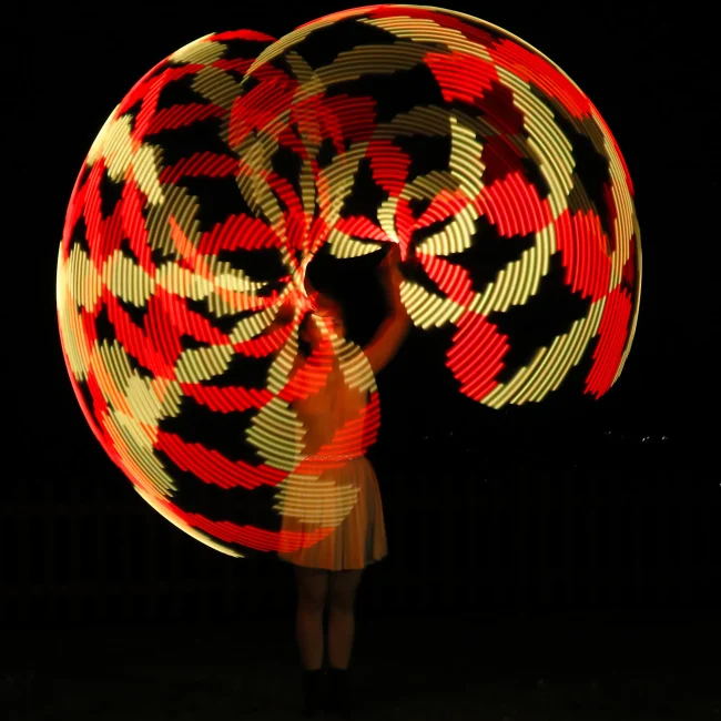 ragazza fa roteare i led nel buio creando un gioco di luci affascinante con i colori rosso e arancione
